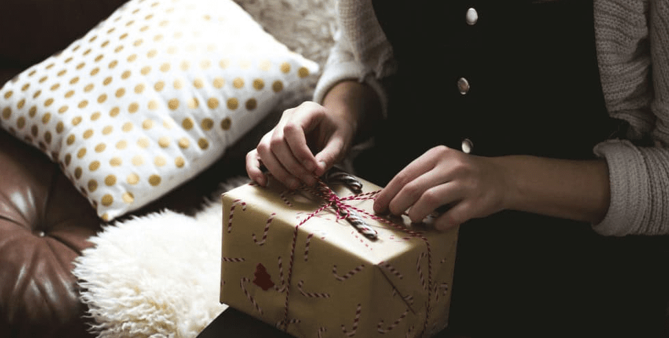 Mulher abrindo embrulho de presente de natal